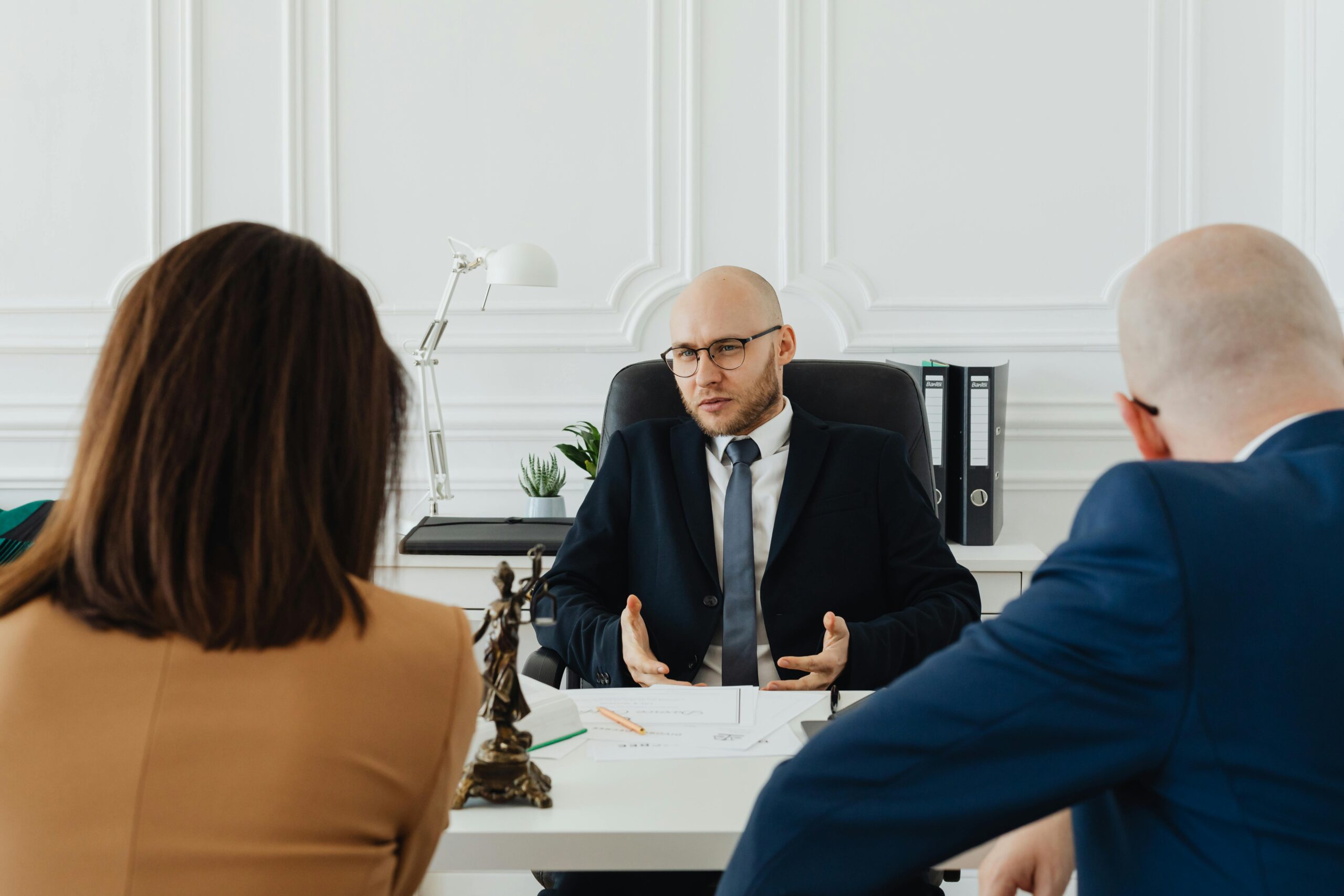 Attorney with glasses at desk discussing collaborative divorce with couple in North Carolina